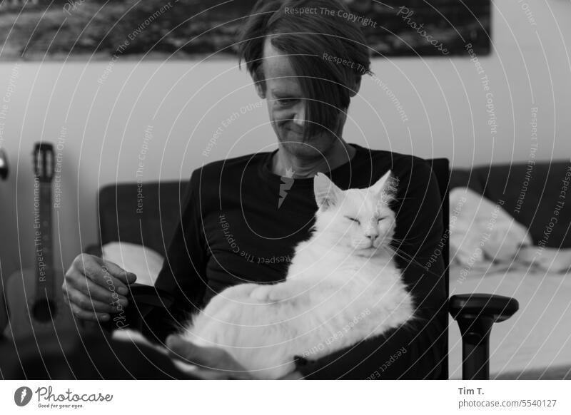 Mann mit Katze s/w weiß Kater bnw Schwarzweißfoto Tag Innenaufnahme
