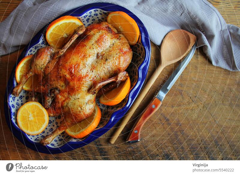 Ganze knusprig goldenen Braten Ente mit mariniert mit frischen Orangenscheiben für eine festliche. Ansicht von oben rustikalen hölzernen Hintergrund.