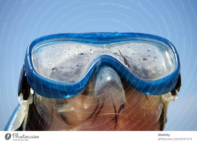 Junge mit blauer Taucherbrille und Schnorchel vor blauem Himmel im Sonnenschein am Strand von Sarimsakli bei Ayvalik am Ägäischen Meer in der Provinz Balikesir in der Türkei