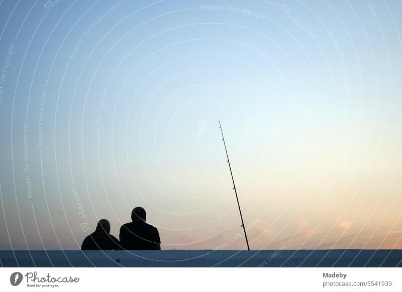 Angler im romantischen Licht der untergehenden Sonne am Abend am Yachthafen von Altinoluk am Golf von Edremit am Ägäischen Meer in der Provinz Balikesir in der Türkei