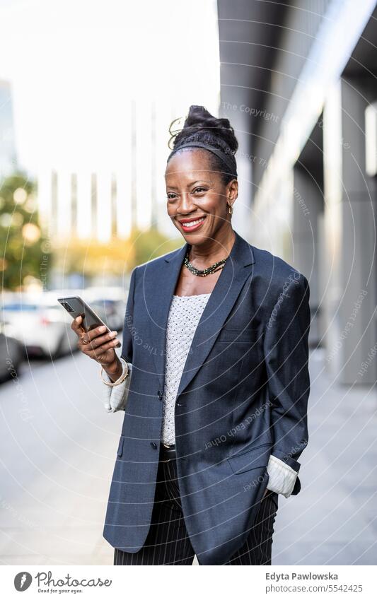 Porträt einer lächelnden reifen Geschäftsfrau, die ein Mobiltelefon in einer städtischen Umgebung benutzt Menschen Stadtzentrum Business Freude Frau urban