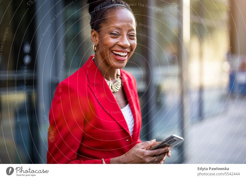 Porträt einer lächelnden reifen Geschäftsfrau, die ein Mobiltelefon in einer städtischen Umgebung benutzt Menschen Stadtzentrum Business Freude Frau urban