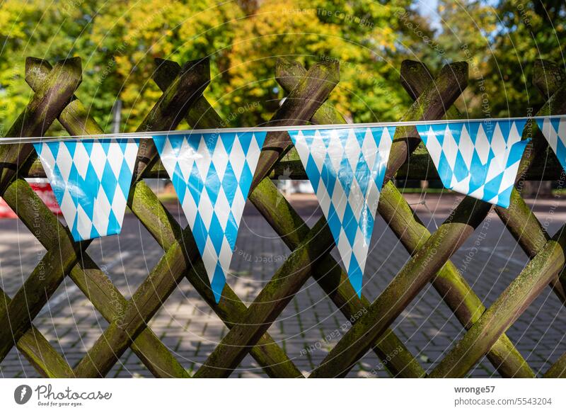 Eine blauweiße Wimpelkette hängt an einem Jägerzaun bayrische Woche Bayern Feste & Feiern mehrfarbig Veranstaltung Holzzaun Werbung Einladung regional