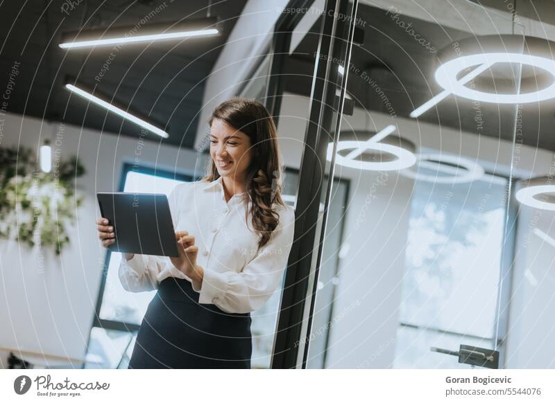 Junge Frau mit digitalem Tablet in einem modernen Büro stehend jung Geschäftsfrau attraktiv Business Technik & Technologie Porträt Stehen Drahtlos Beruf