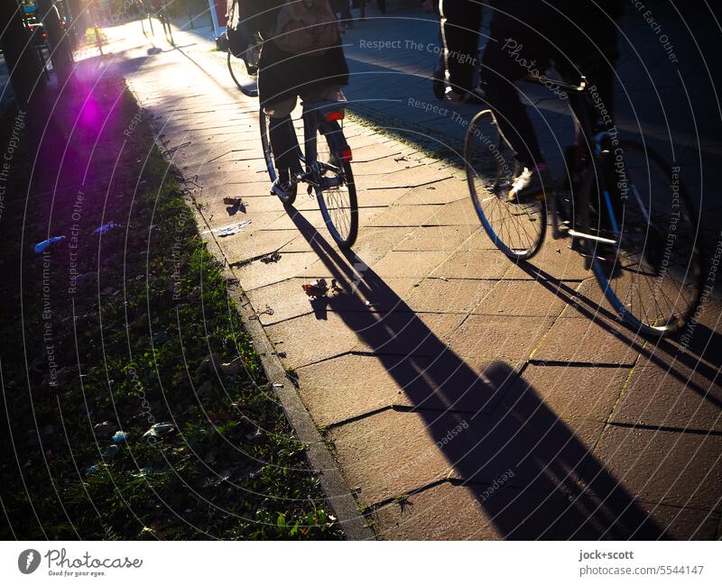 Fahrradfahren in der Stadt Biker Radfahrer Bürgersteig Lifestyle Schatten Silhouette urban Bewegung Berlin Bodenplatten Wärme Schattenspiel Sonnenlicht