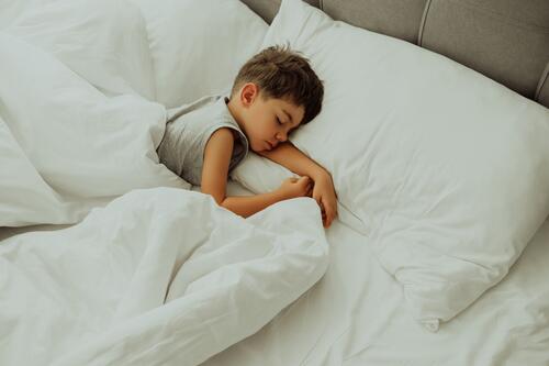 Ruhiges kleines Kind schläft gut in einem bequemen Bett. Junge in hellem, gemütlichem Schlafzimmer. Kindheit niedlich bezaubernd schlafend Kaukasier träumen