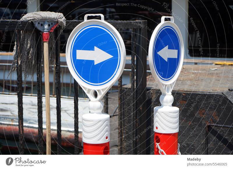 Ständer in Rot und Weiß mit blauen runden Verkehrszeichen mit weißem Richtungspfeil an der Anlegestelle der Fähre in Eminönü an der Galatabrücke in Istanbul am Bosporus ihn der Türkei