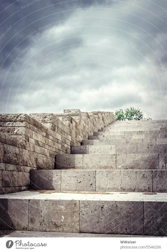 Eine steile Treppe aus großen schweren Steinblöcken führt irgendwo nach oben Stufen steigen hoch hinauf Wand Marmor draußen Blöcke modern Himmel wolken