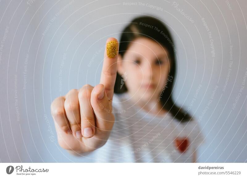 Ernstes junges Mädchen schaut in die Kamera und zeigt ihren mit goldenem Glitter bedeckten Finger zeigend Mikroplastik Kunststoff gestikulieren Problematik