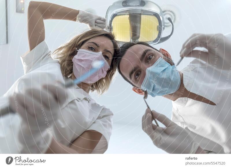Zwei Zahnärzte mit Gesichtsmasken und Gummihandschuhen, niedrige Winkelaufnahme Zahnarzt Zahnmedizin Gesundheitswesen Frau Klinik dental Arzt Krankenhaus