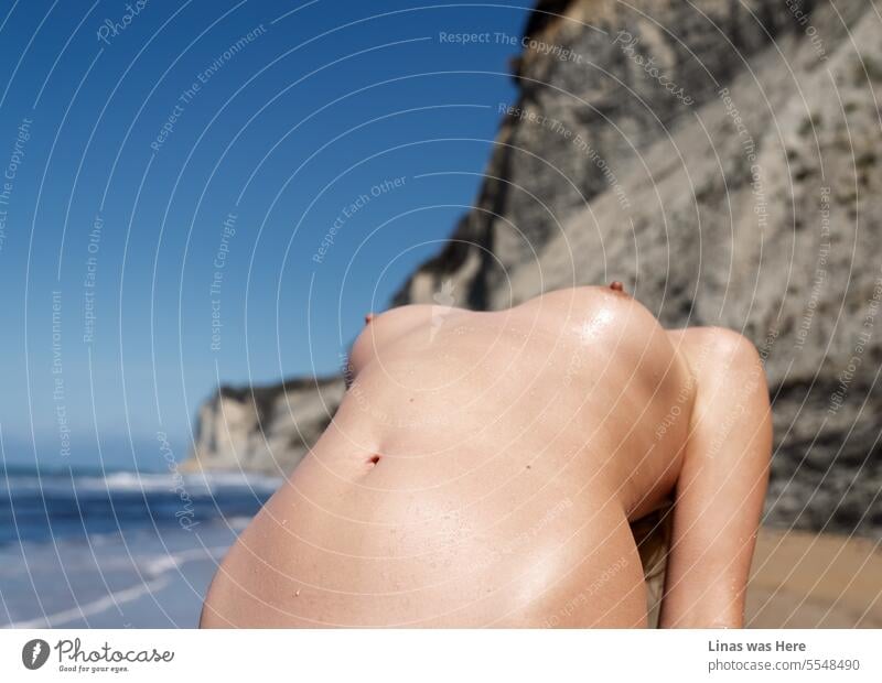 Ein wunderschöner nackter Körper einer hübschen Frau liegt vor Ihnen. Ihre sexy Kurven vor der Kulisse der felsigen Küste, dem blauen Himmel und dem goldenen Sandstrand in Korfu, Griechenland. Ein lustvoller Urlaub ist voll von Liebe.