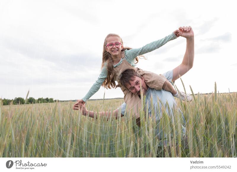 Ein Mädchen und ihr Vater sind glücklich und spielen vor der Kulisse eines landwirtschaftlichen Feldes. Licht laufen Freude Tag Wachs Ohr Ohren Brot Roggen