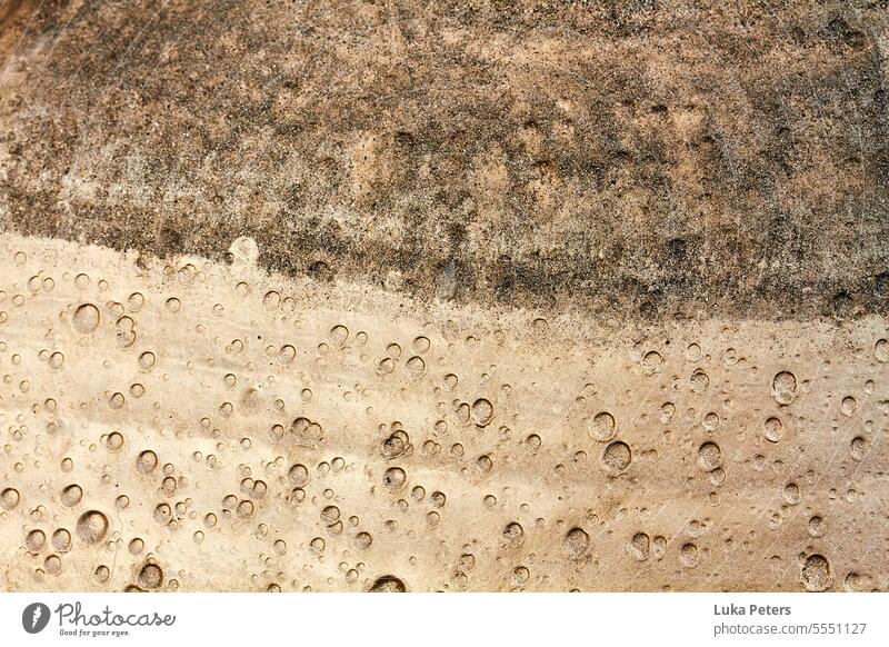 Eine farblich zweigeteilte Aufnahme von nassem Sand mit Luftblasen, braun und bronzefarben. Strukturen & Formen abstrakt Natur natürlich Hintergrund