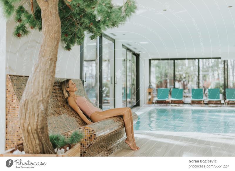 Junge Frau entspannt sich am Hallenbad Schönheit Schwimmsport Wohlbefinden im Innenbereich Beckenrand aussruhen Erholung Menschen Wasser Blick