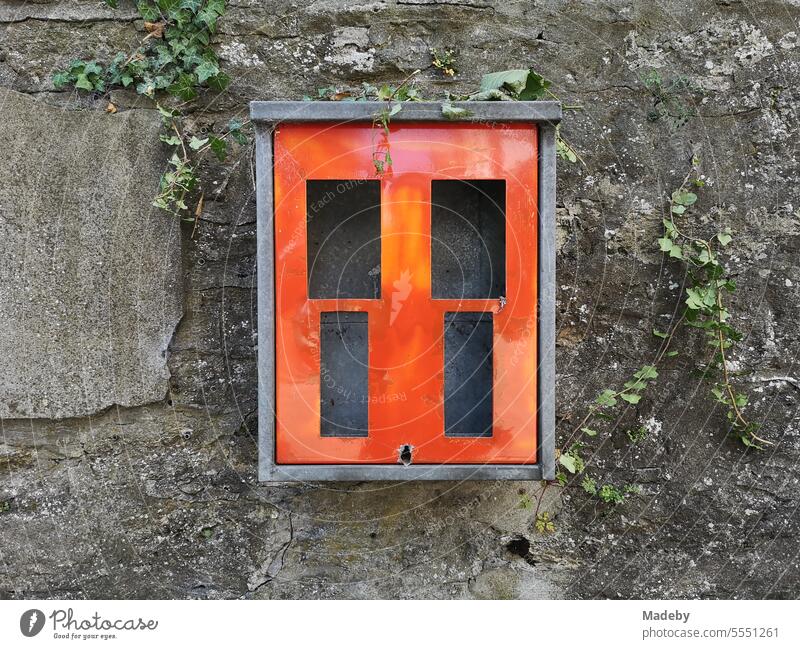 Ausrangierter roter Kaugummiautomat für Kinder an einer alten Mauer aus Naturstein mit Unkraut in der Altstadt von Oerlinghausen bei Bielefeld am Hermannsweg im Teutoburger Wald in Ostwestfalen-Lippe