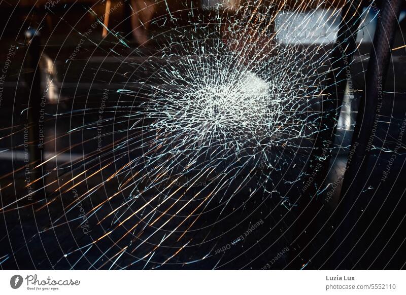 Splitter im Glas einer Ladentür, Dunkelheit und Reste von Straßenlicht Sprünge Risse Scherben Zerbrochenes Fenster Vandalismus Fensterscheibe Vergänglichkeit