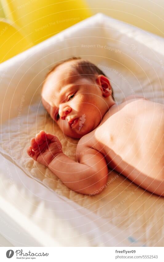 Porträt eines Neugeborenen auf einer Wickelkommode Baby neugeboren Sonnenlicht Textfreiraum Elternschaft Mutterschaft Unschuld Leben Wehen jung Junge Glück Born