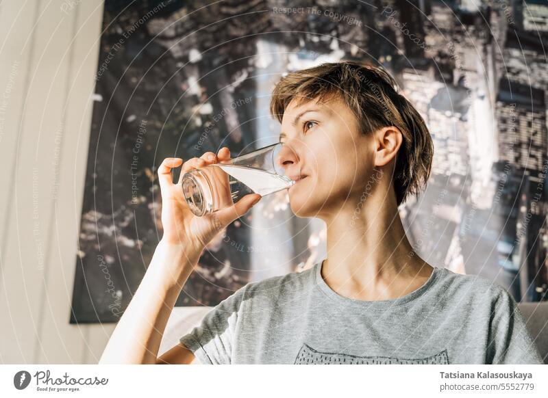Eine junge Frau mit kurzen Haaren trinkt Wasser aus einem Glas Menschen Lifestyle trinken Person Kaukasier 30-40 Jahre Gerichte Wasserglas Windstille