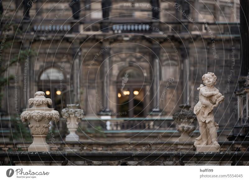 barocker Engel mit weiteren Zierelementen  vor einem alten Schloss Barock Putten Skultptur Zwinger Schwache Tiefenschärfe historisch Denkmal Wahrzeichen