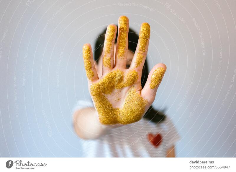 Unbekanntes junges Mädchen zeigt ihre Handfläche mit goldenem Glitter, während sie ein Stoppschild macht unkenntlich stoppen Zeichen Mikro Kunststoff