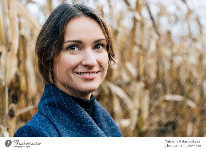 Glücklich lächelnde Frau im Herbst im Kornfeld Lächeln Mantel Reihen Mais Feld fallen im Freien ländlich Landschaft Ernte saisonbedingt landwirtschaftlich