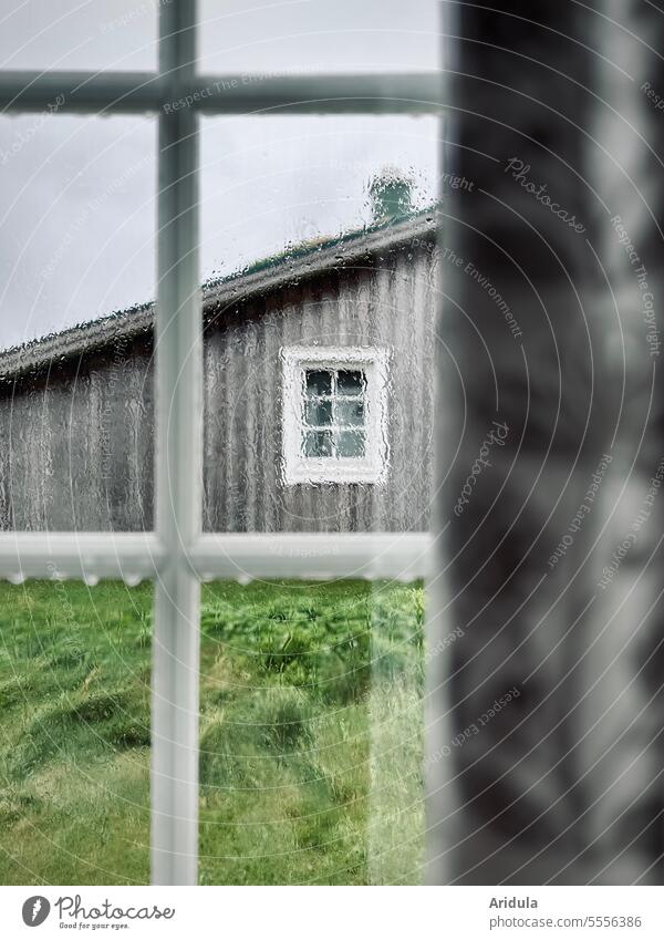 Blick aus dem Fenster auf ein Holzhaus im Regen Regentropfen Regenwetter nass Sprossenfenster trüb trist schlechtes Wetter Wassertropfen Herbst grau kalt
