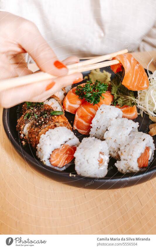 Nahaufnahme eines Sushi-Tellers mit weiblichen Händen und Stäbchen Lifestyle Gesundheit Fisch Essstäbchen Japanisch lecker Speise Amuse-Gueule geschmackvoll
