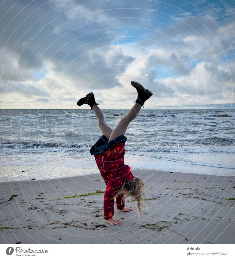 Kind macht Handstand am Strand Bewegung Sport sportlich Lebensfreude Sand Meer über Kopf Himmel Freude Mensch Spielen Kindheit Außenaufnahme Wolken Wasser Kraft