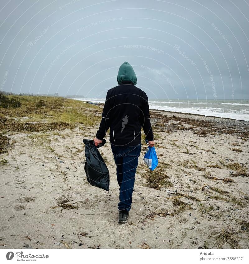 Mann geht mit zwei Tüten in der Hand am Strand entlang zum Müll einsammeln Mülltüten Umwelt Umweltverschmutzung Küste Meer Kunststoff Natur Recycling Sand
