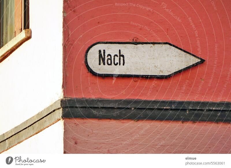altes Schild mit der Aufschrift  " Nach " an einem rot verputzten Haus / Wegweiser Hinweisschild Richtung Hauswand richtungsweisend Orientierung Wohnhaus