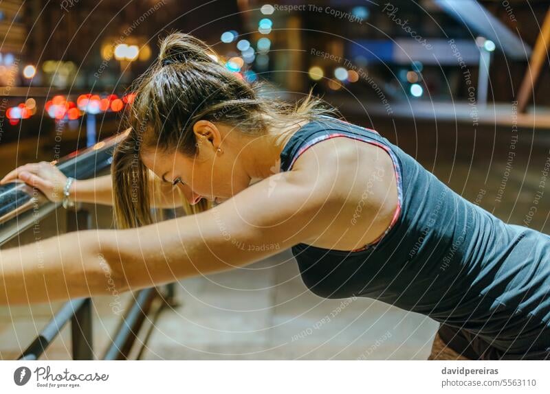 Porträt einer jungen Sportlerin, die sich nach einem nächtlichen Training in der Stadt über einem Geländer ausruht. Frau erschöpft müde aussruhen Athlet Läufer