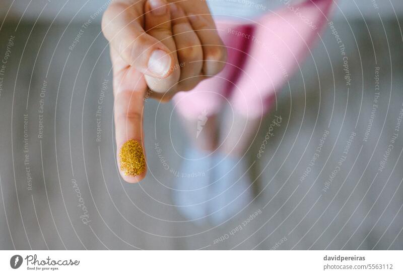Unbekanntes Kind zeigt Finger mit goldenem Glitter, der aus schädlichen kleinen Kunststoffen besteht unkenntlich Mikro zeigend Mikroplastik Hand Verbot Europäer