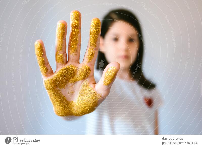 Ernstes junges Mädchen zeigt ihre Handfläche mit goldenem Glitter, während sie ein Stoppschild macht stoppen Zeichen Mikro Kunststoff Mikroplastik gestikulieren