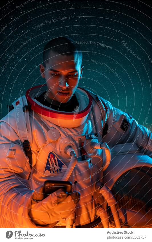 Astronaut im Raumanzug hält Helm, während er auf seinem Smartphone surft Kosmonaut Konzept erkunden Galaxie Schmuckkörbchen Schutzhelm Browsen Astronomie