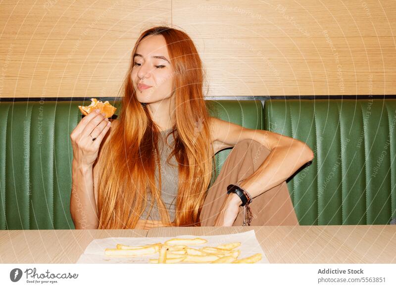 Junge Frau isst gerne Hamburger Mädchen essen Fastfood Burger jung Lebensmittel Tisch Sitzen eine Abendessen Mittagessen Snack Beteiligung Hand ungesund