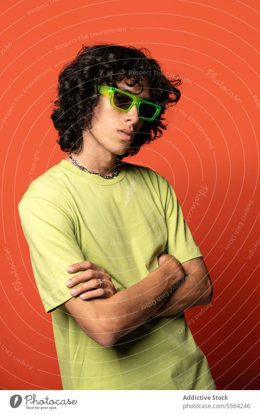 Selbstbewusster junger ethnischer Mann mit Sonnenbrille in der Nähe eines türkisfarbenen Hintergrunds flippig Tänzer Mode krause Haare cool Individualität