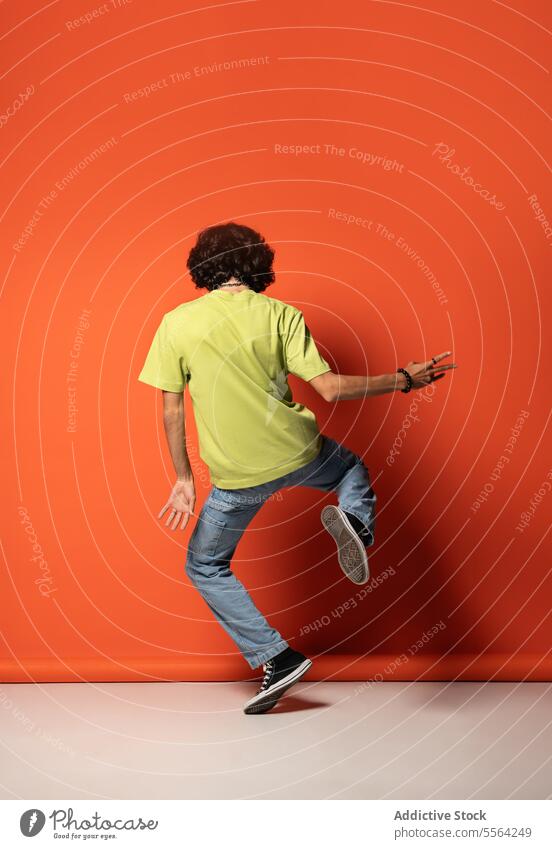 Unbekannter Mann mit dunklem Haar tanzt an einer roten Wand Tanzen Bein angehoben Tänzer Schatten ausführen sich[Akk] bewegen beweglich Licht Energie männlich