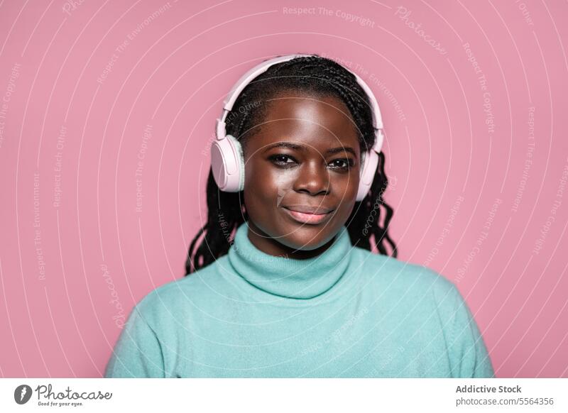 Afrikanische Frau mit Kopfhörern rosa Hintergrund Nahaufnahme Porträt Musik Hörer Freude Technik & Technologie Audio Entertainment Gesicht Ausdruck Windstille