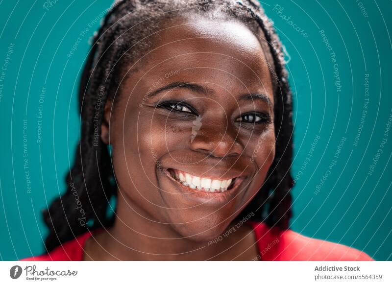 Afrikanische Frau in roter Bluse türkis Hintergrund geflochten Behaarung Hals Porträt Gesicht Schönheit Kultur schwarz jung Erwachsener melanin ernst Ausdruck