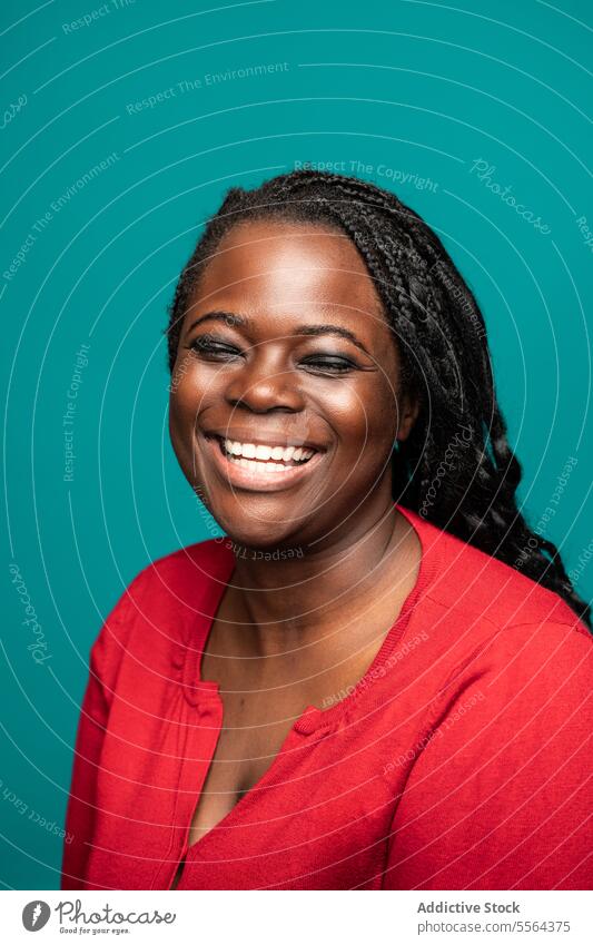 Warmes Lächeln einer afrikanischen Frau vor einem blaugrünen Hintergrund Nahaufnahme Afrikanisch rot Bluse warm Auge Zähne Haut Gesicht Schönheit Emotion