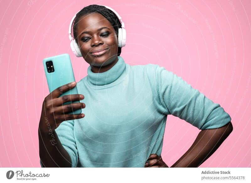 Afrikanische Frau macht Selfie mit Smartphone türkis Pullover Minze grün rosa Kopfhörer Hintergrund Pose einfangen Foto Mobile Gerät Mode Technik & Technologie