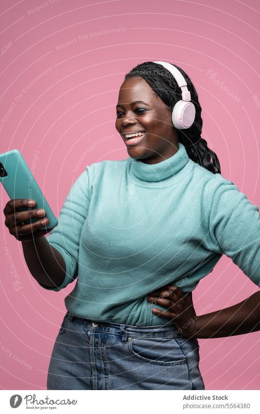 Afrikanische Frau genießt Musik mit Smartphone türkis Pullover Freude rosa Kopfhörer Minze grün Hintergrund Genuss Mode Technik & Technologie Stil Freizeit