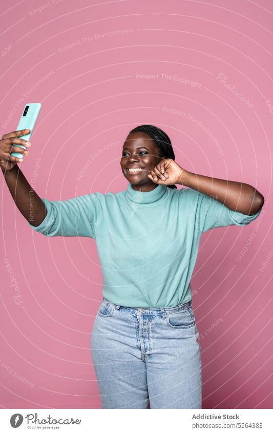 Afrikanische Frau macht Selfie mit Smartphone vor rosa Hintergrund Telefon Freude Lächeln Pose Technik & Technologie Foto Mobile einfangen Moment heiter Porträt