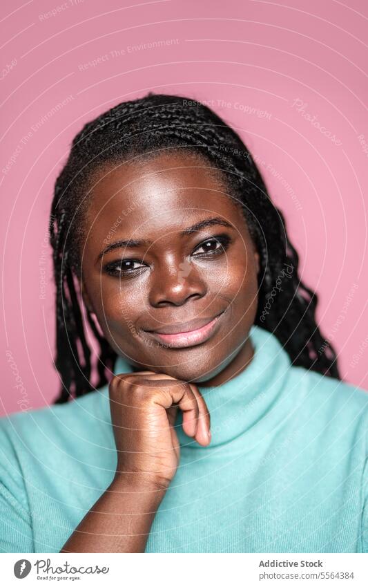 Lächelnde Afrikanerin in mintgrünem Rollkragenpullover Afrikanisch Frau rosa Hintergrund Minze Rollkragenpulli Zopf Behaarung Fröhlichkeit Schönheit Mode