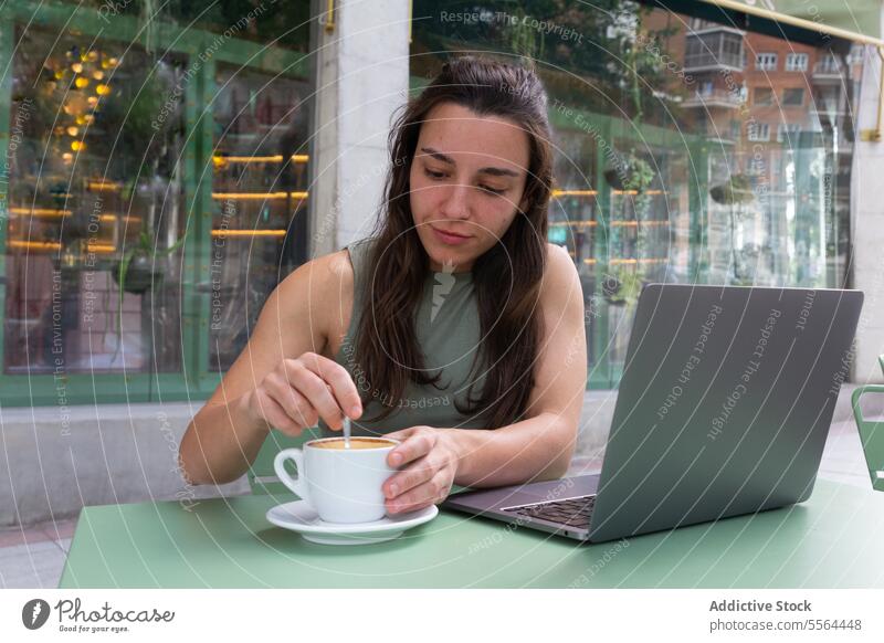 Frau gibt Zucker in eine Tasse Kaffee im Café freiberuflich abgelegen Internet Inbetriebnahme Laptop Arbeit Glück Lächeln Arbeitsplatz online Browsen Surfen