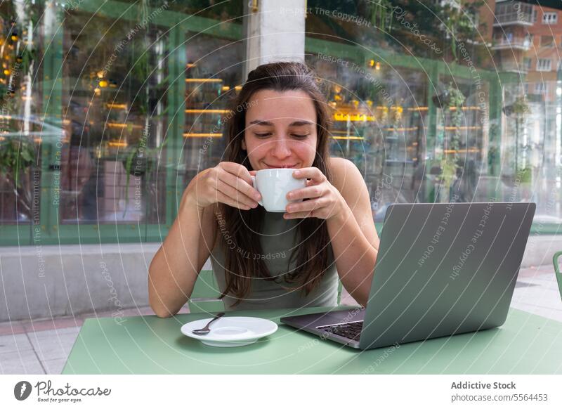 Junger Freiberufler trinkt heißen Kaffee in einem Café Frau freiberuflich trinken abgelegen Arbeit Laptop Glück Apparatur jung Tisch Heißgetränk Lächeln