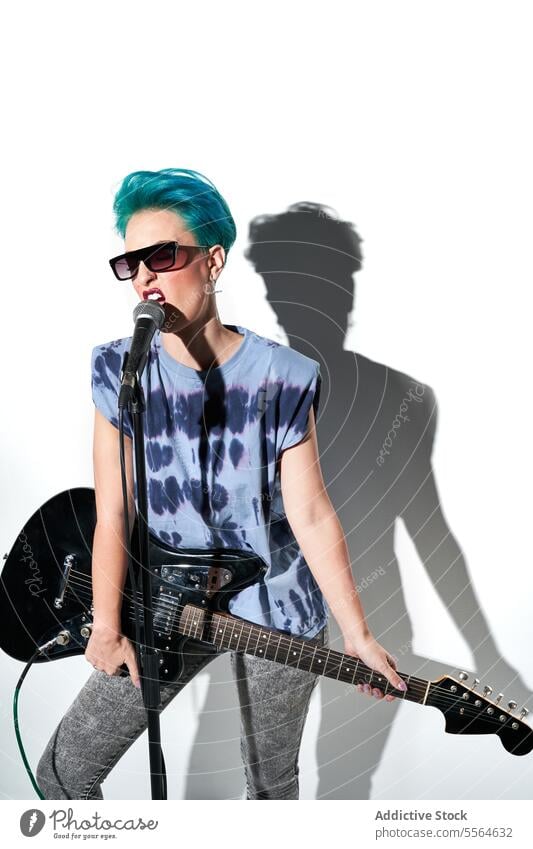Energetischer weiblicher Rockstar spielt Gitarre in einem hellen Studio auf weißem Hintergrund Frau Musiker spielen ausführen Stil Instrument nachdenklich