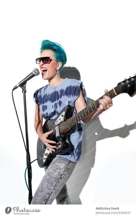 Energetischer weiblicher Rockstar spielt Gitarre in einem hellen Studio auf weißem Hintergrund Frau Musiker spielen ausführen Stil Instrument nachdenklich