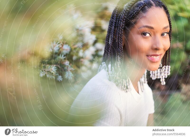 Lächelnde afroamerikanische Frau in einem blühenden Garten mit Blumen Park Blütezeit Natur Sommer Flora jung lässig sitzen sich[Akk] entspannen Geflecht Stil