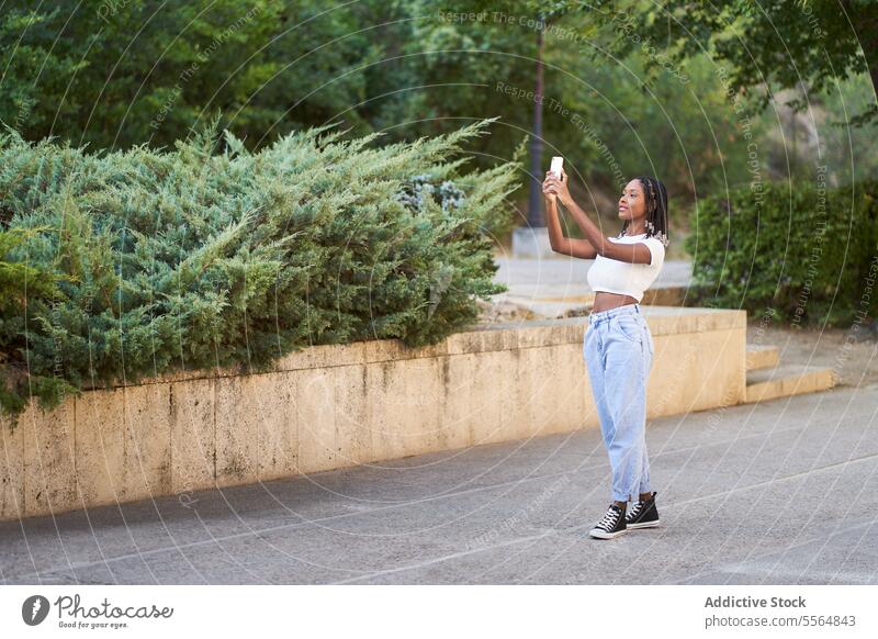 Afroamerikanische Frau macht Selfie mit Smartphone Glück Park fotografieren Telefon Mobile benutzend Gerät Baum Funktelefon Moment Buchse soziale Netzwerke